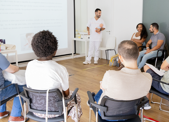 Sessão prática do curso de preparação para o parto da Cintramédica em Sintra com o formador e casais. Aula de preparação para o parto com explicações sobre cuidados ao bebé