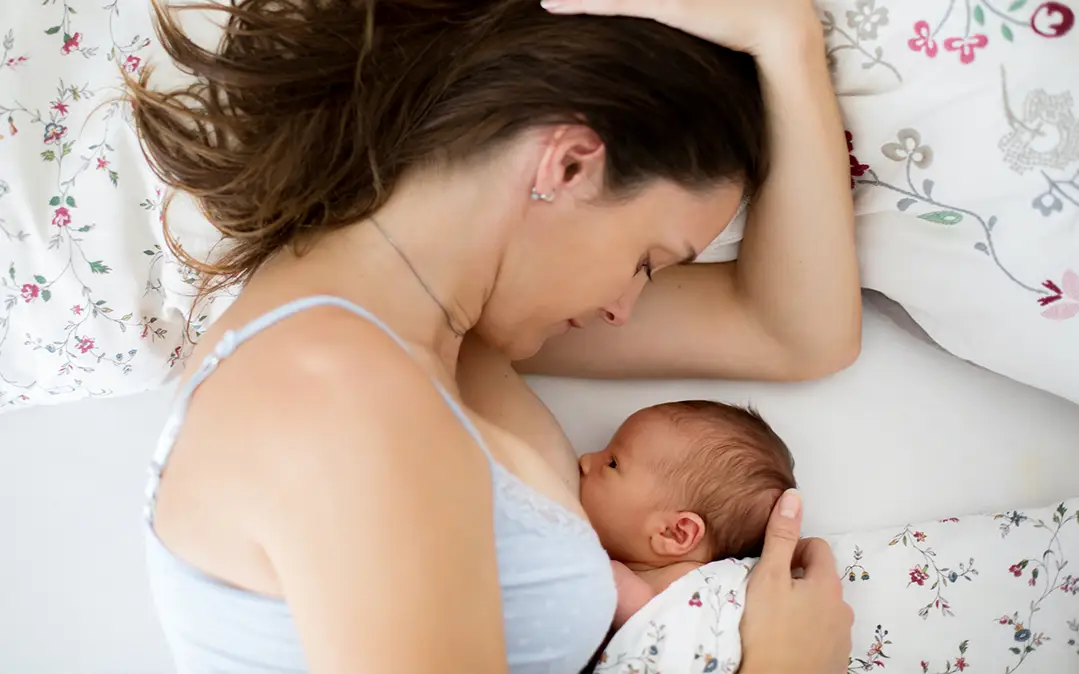 mulher, deitada, amamenta bebé recém-nascido