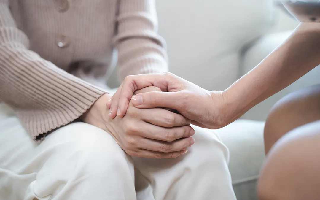 Duas pessoas de mãos dadas, ilustrando o apoio emocional durante o diagnóstico e tratamento do Cancro da Mama.