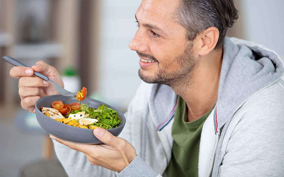 homem come uma salada, com o objetivo de controlar os níveis de Colesterol