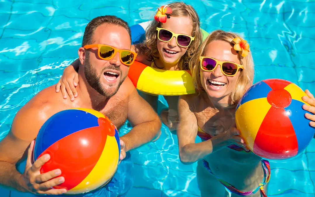 família, com ar muito feliz, a brincar na piscina, a aproveitar o verão