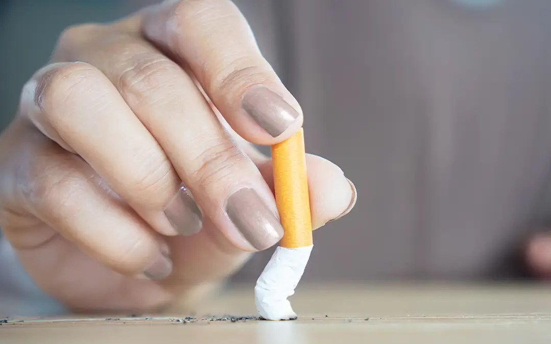 mão feminina, com unhas pintadas, esmaga um cigarro, como forma de mostrar que pretende deixar de fumar