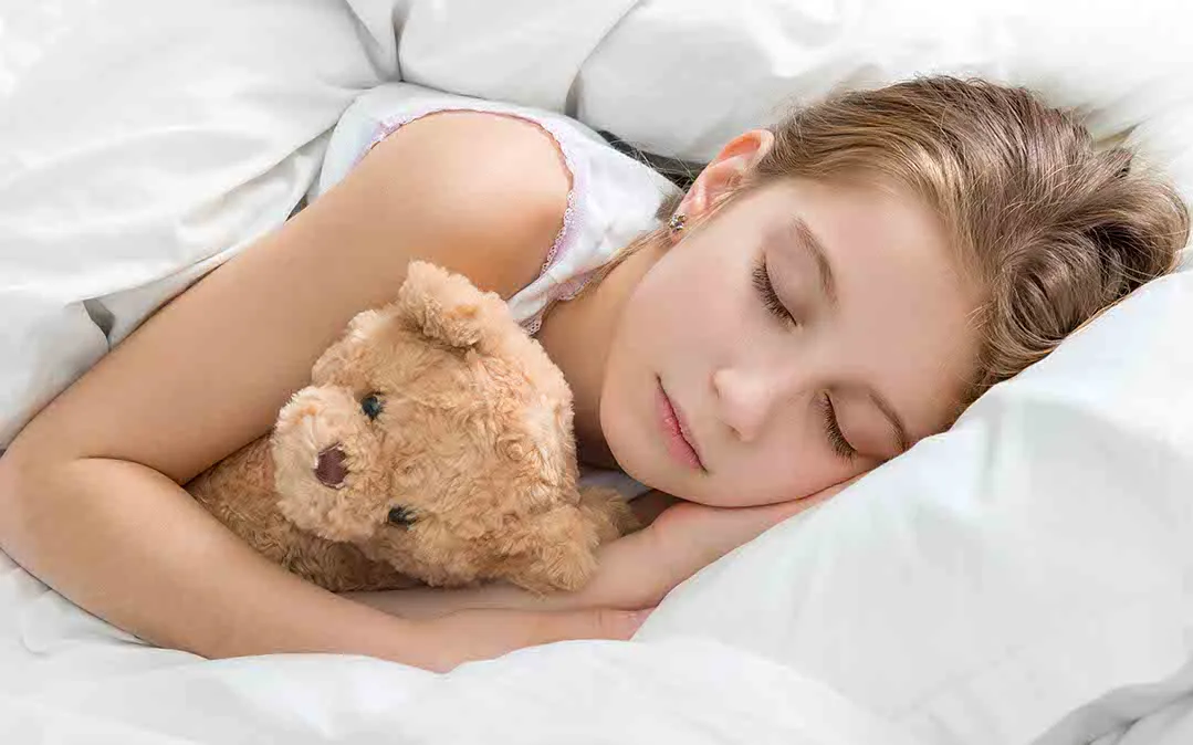 rapariga a dormir tranquilamente  abr4açada com o seu urso de peluche 