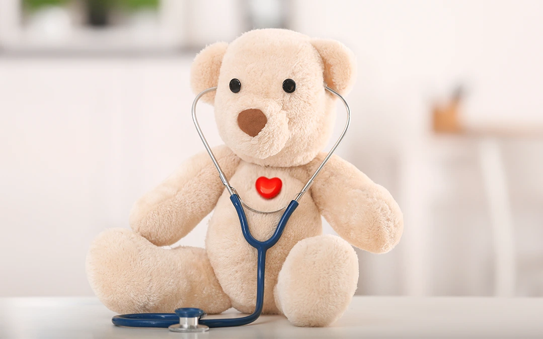 urso de peluche com um coração vermelho e um estetoscópio a incentivar o tratamento e prevenção cardiológica pediátrica 